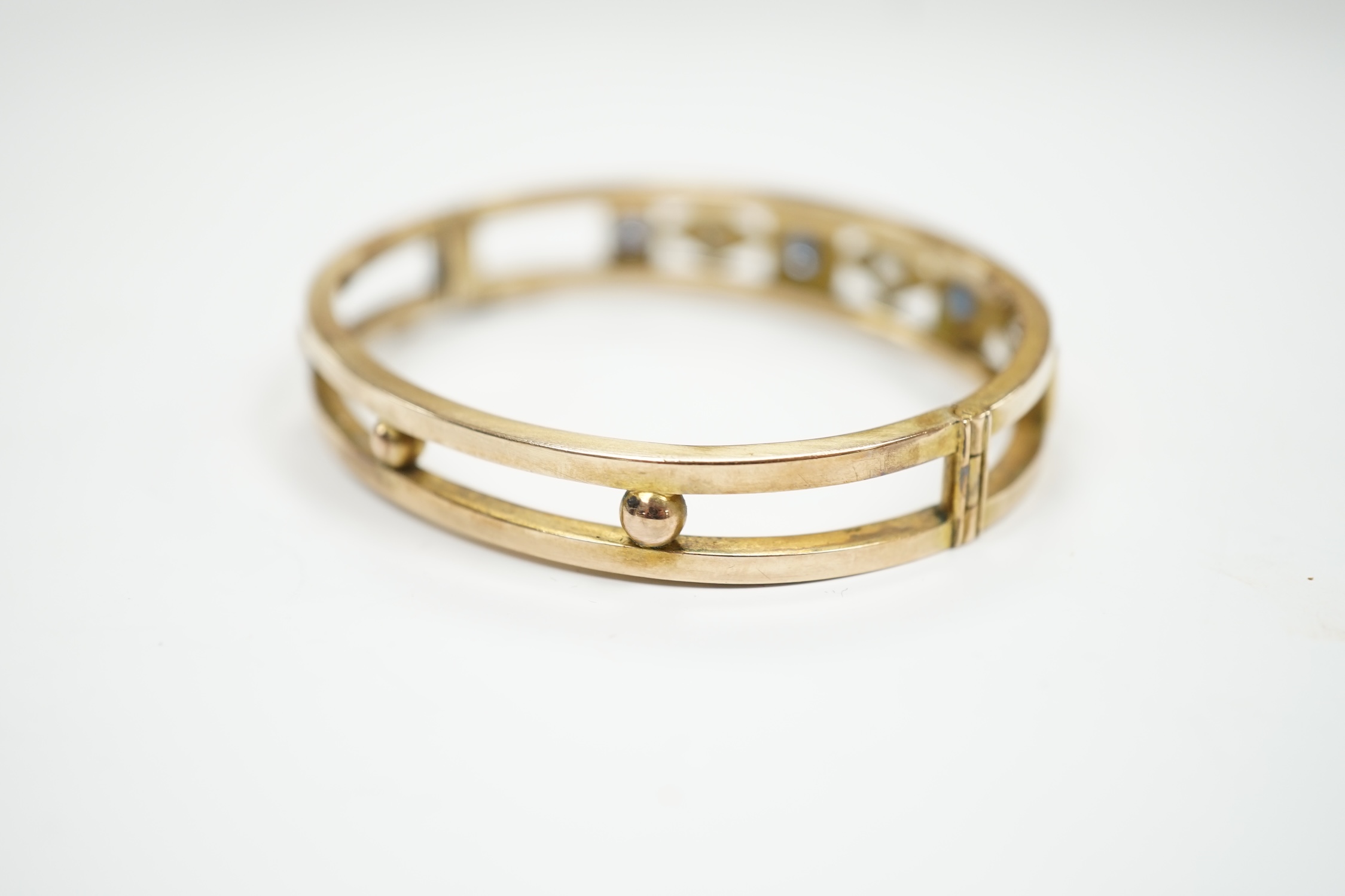 An Edwardian yellow metal, sapphire and diamond set hinged bangle, interior diameter 55mm, gross weight 14.4 grams, with box.